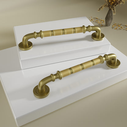 Two gold cabinet handles on a white surface with a neutral background